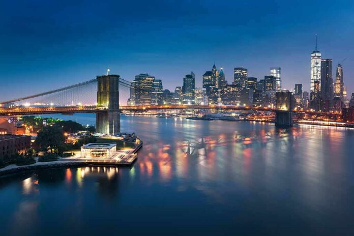 shutterstock_1620784198 Brooklyn Bridge over river with illuminated city skyline at dusk