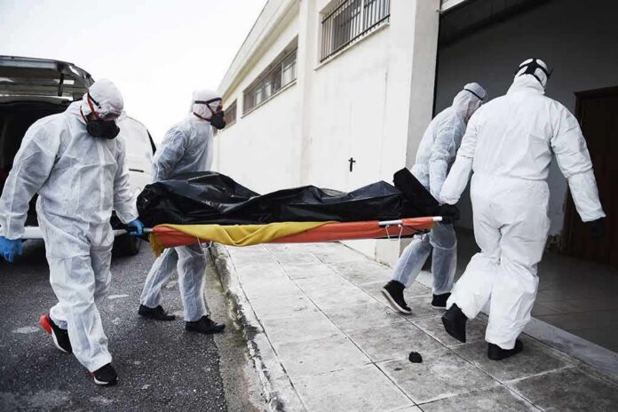 shutterstock_1693125517-2 medical team in hazmat suits carrying a body on a stretcher