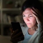 Woman looking at smartphone with worried expression