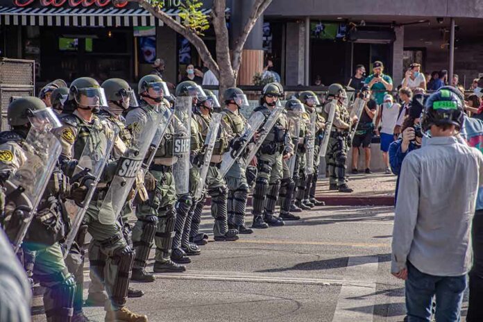 shutterstock_1756892879-1 Riot police in helmets and shields form a line on a city street
