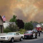 Emergency vehicles respond to wildfire near suburban homes