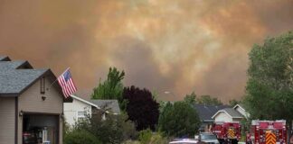 Emergency vehicles respond to wildfire near suburban homes
