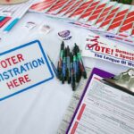 Trump Pushes Nationwide Voter Purge Voter registration table with forms, pens, and informational materials