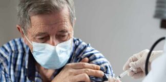 Older man in mask receiving a vaccine injection