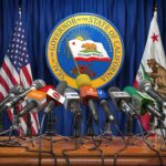 California vs. Feds: Showdown Loaded Press microphones at a podium before California governor seal