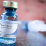 Fentanyl vial on a table with blurred syringe in background