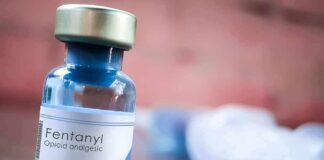 China’s Fentanyl Role Sparks U.S. Debate Fentanyl vial on a table with blurred syringe in background