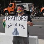 Protester holding a sign with Benedict Arnold portrait at a street demonstration