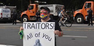 Protester holding a sign with Benedict Arnold portrait at a street demonstration