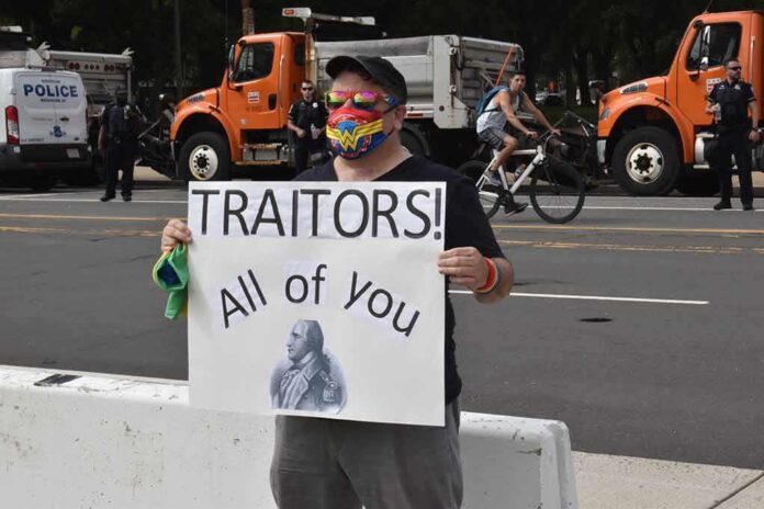 shutterstock_2043483539 Protester holding a sign with Benedict Arnold portrait at a street demonstration