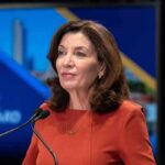 Kathy Hochul speaking at a podium with microphones
