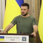 Zelensky Meeting Triggers Shocking U-Turn Man at a podium with Ukrainian flags