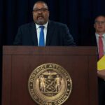 Man speaks at podium with New York County District Attorney seal