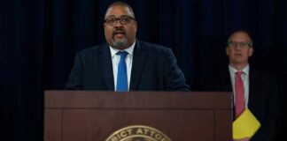 Man speaks at podium with New York County District Attorney seal