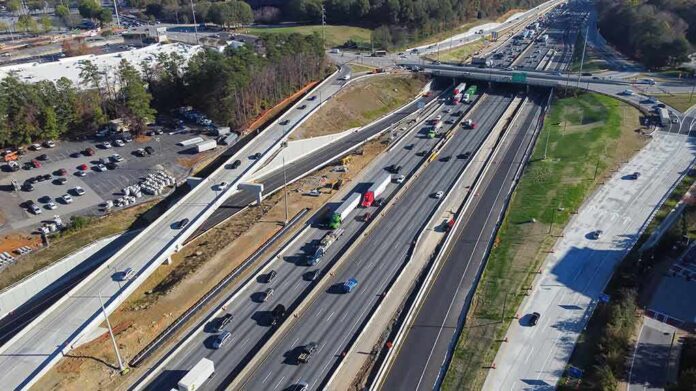 shutterstock_2268382443 Aerial view of multi-lane highway interchange with overpass and traffic