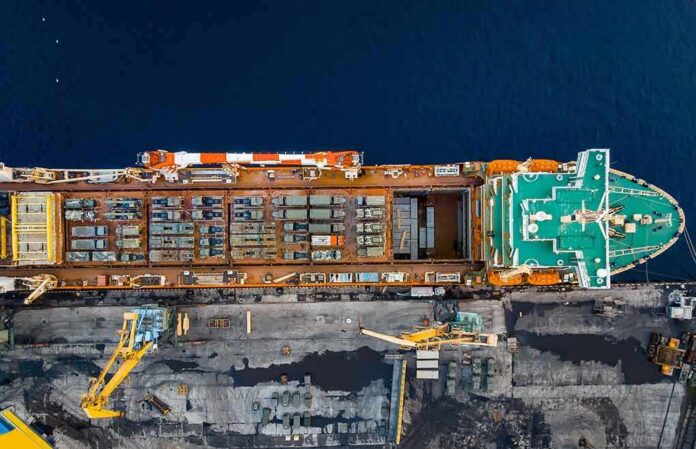 shutterstock_2271735907 Cargo ship docked at port seen from above