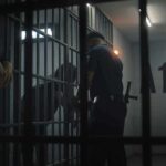 police officer at a jail cell with detainees behind bars