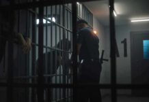 NYC Jail Death Sparks Debate police officer at a jail cell with detainees behind bars