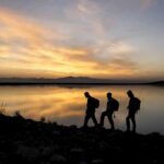Week-Long Vanish: Coast Guard Rescues Missing Hiker hikers silhouetted by a lake at sunset
