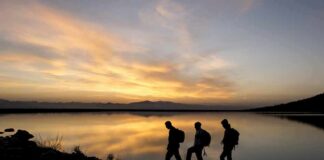 Week-Long Vanish: Coast Guard Rescues Missing Hiker hikers silhouetted by a lake at sunset