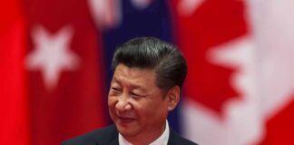 Trump’s Xi Welcome Revives Old Criticism man in suit against red and white flags