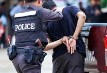Police officer escorting a handcuffed man to a vehicle