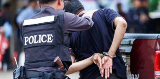 Police officer escorting a handcuffed man to a vehicle