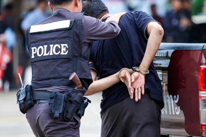 Police officer escorting a handcuffed man to a vehicle