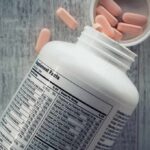 Vitamin supplement bottle with pink tablets and nutrition label