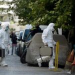 forensic investigators in white protective suits walking on a city street
