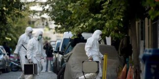 forensic investigators in white protective suits walking on a city street