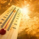 A thermometer displaying temperature against a sunset sky
