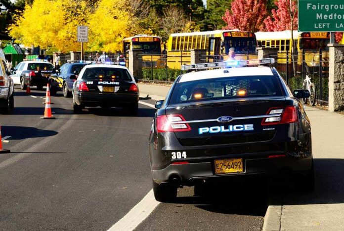 Roseburg,,Or,-,October,16:,Police,Cars,And,School,Buses Police cars with lights on near school buses on a city street