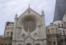 Stone church facade with large rose window and cross