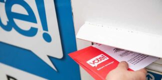 NC Mail Ballot Rejections Rise Slightly Hand inserting mail-in ballot envelope into drop box