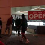 France Faces Unrest Amid Rising Living Costs People outside a storefront with broken glass at night