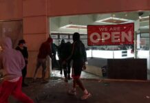 France Faces Unrest Amid Rising Living Costs People outside a storefront with broken glass at night