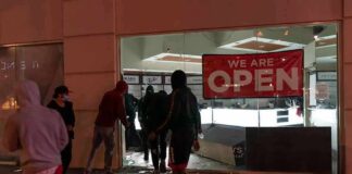 People outside a storefront with broken glass at night