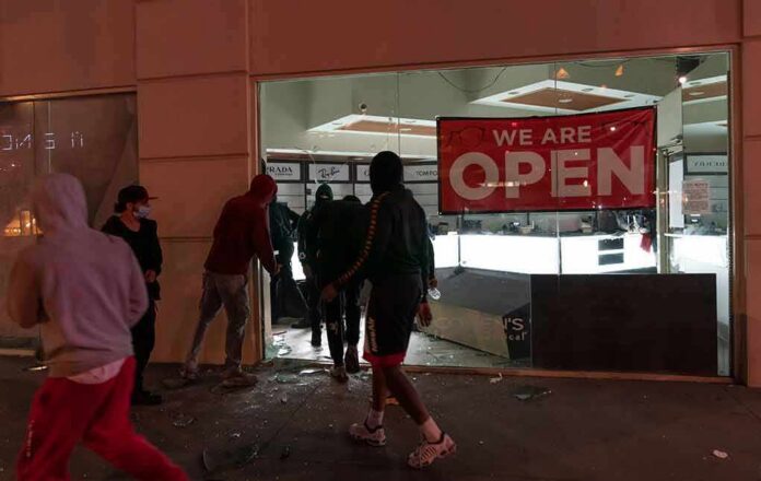shutterstock_1747500206 People outside a storefront with broken glass at night