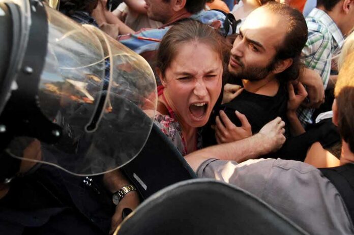 Protesters clash with riot police as woman shouts