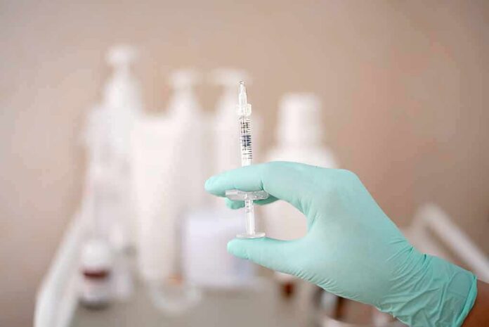shutterstock_1990198511 Gloved hand holding a syringe