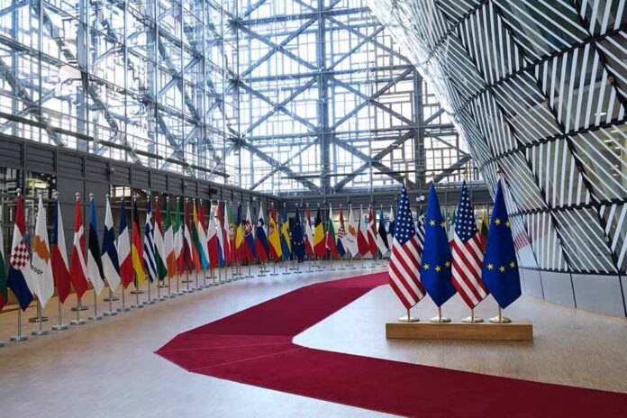 Row of national flags in a modern glass atrium with red carpet and EU and US flags upfront