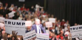 Trump Rally Draws Rain-Soaked Crowd supporters hold signs at a political rally