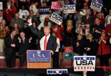 Donald Trump addresses a rally crowd at a podium, raising his fist
