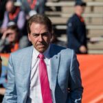 Trump Plans Alabama-Georgia Game Appearance Nick Saban in a light blue plaid suit with a pink tie at a football stadium; Chuck Howley not visible