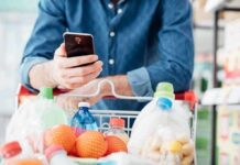 Shopper using smartphone over a grocery cart