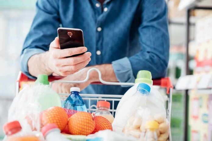 Shopper using smartphone over a grocery cart