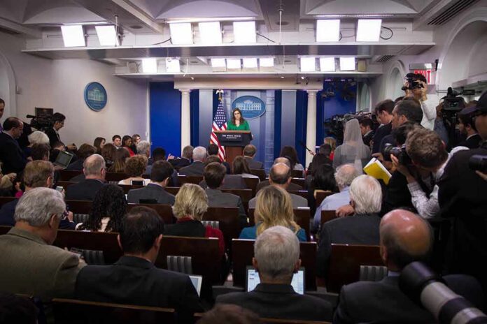 shutterstock_744405130-2 Press secretary at podium addressing reporters in briefing room